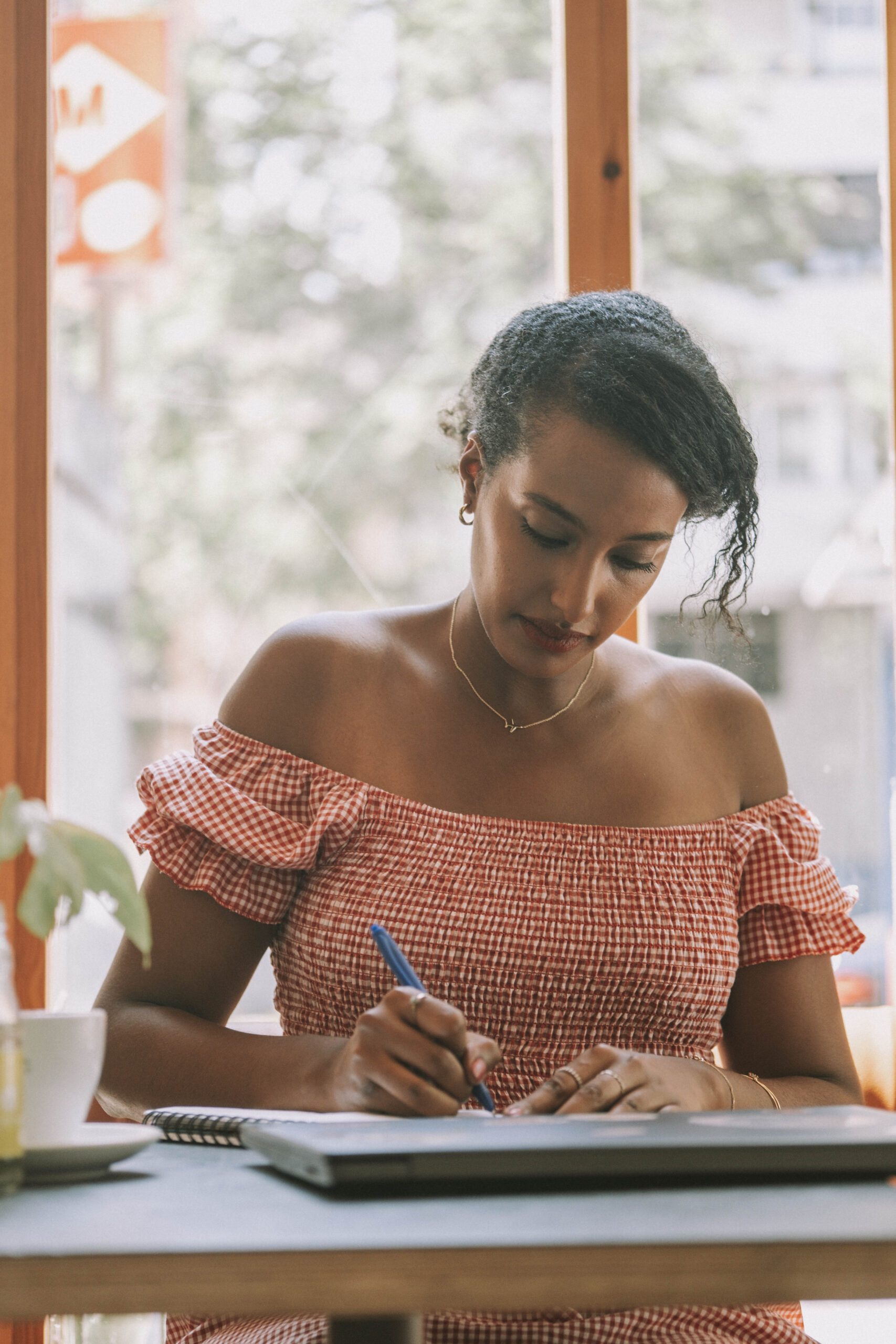 Black female digital nomad working on laptop at a café