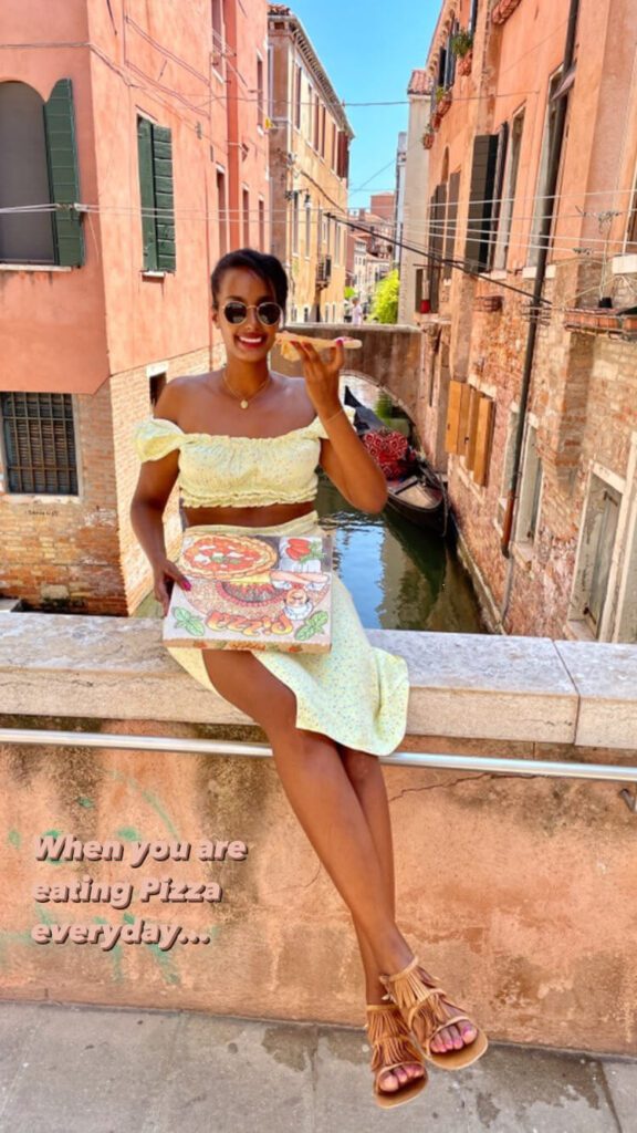 Solo female traveler eating pizza alone in Venice, Italy with canal view