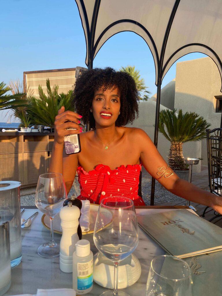 Solo female traveler enjoying dinner in Rhodes, Greece, practicing self-care tips while traveling alone