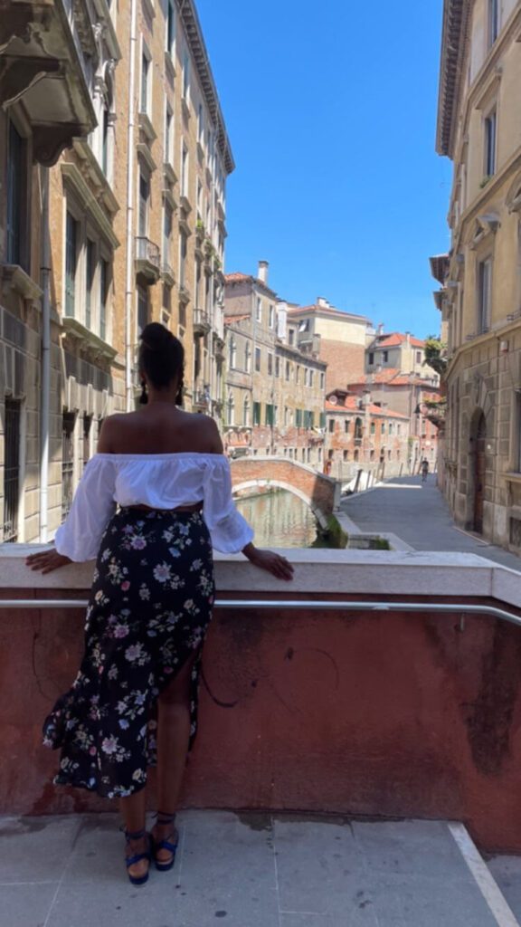 Solo female traveler eating pizza in Venice, Italy, with a view of the canals