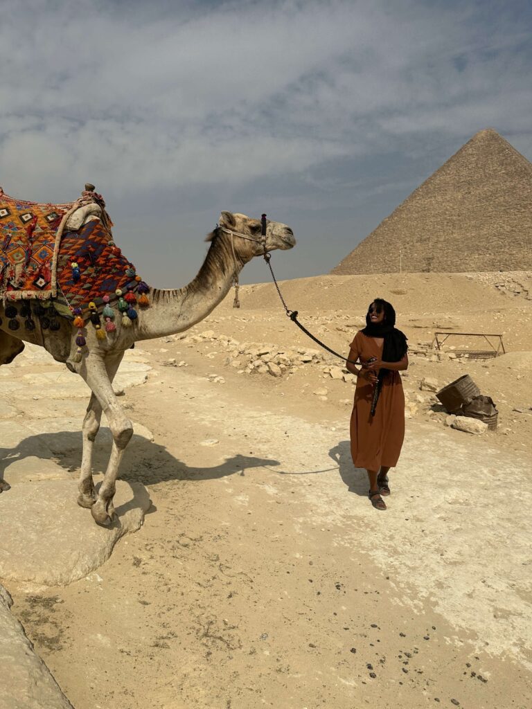 Woman traveling solo with camel near Egyptian pyramids
