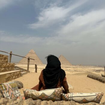 Solo female traveler relaxing alone at the Great Pyramids of Giza in Cairo, Egypt