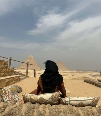 Solo female traveler relaxing alone at the Great Pyramids of Giza in Cairo, Egypt