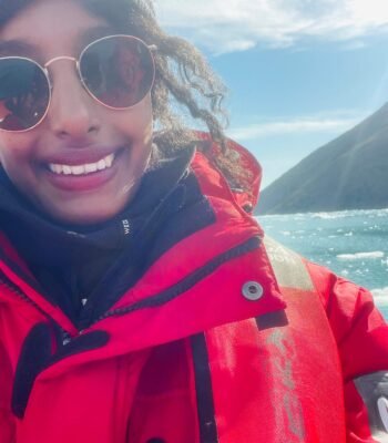 Solo female traveler exploring Greenland with Zodiac boat tour, enjoying icy landscapes and adventure.