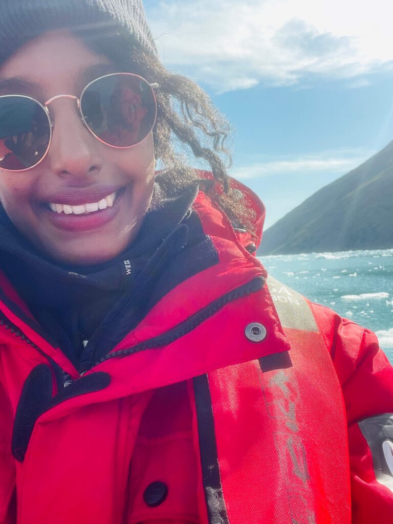 Solo female traveler exploring Greenland with Zodiac boat tour, enjoying icy landscapes and adventure.