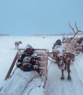 Solo female traveler riding reindeer sled in Norway