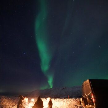 Solo female traveler hiking in Tromsø mountains with snowy landscape