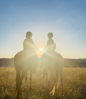Two female travelers riding horses at sunset in Turkey