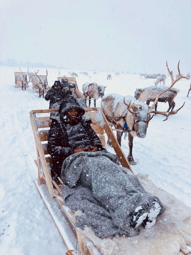 Solo female traveler in Tromsø enjoying a reindeer sledding experience in the Arctic
