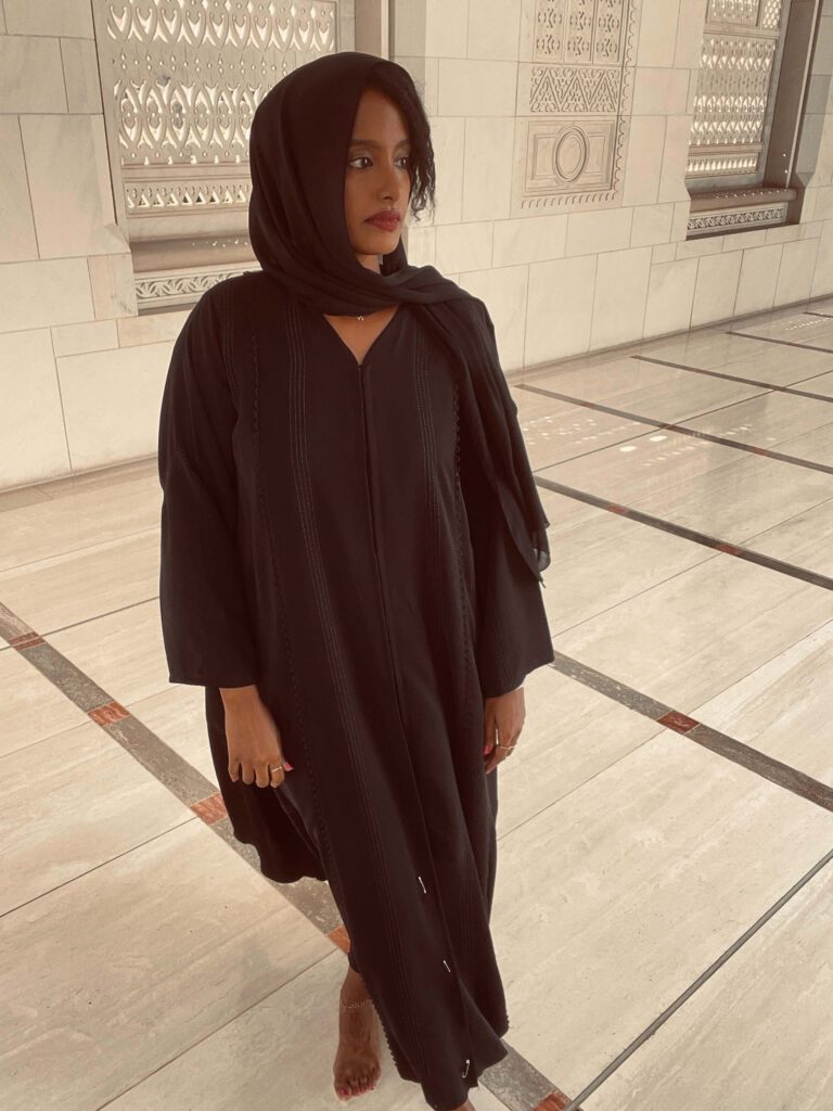 Solo female traveler visiting a beautiful mosque in Oman, exploring local culture and architecture.