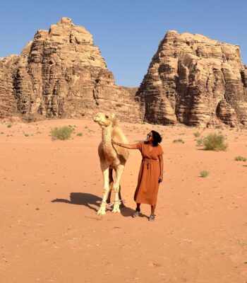 Solo female traveler riding a camel in the desert of Jordan, adventure travel experience