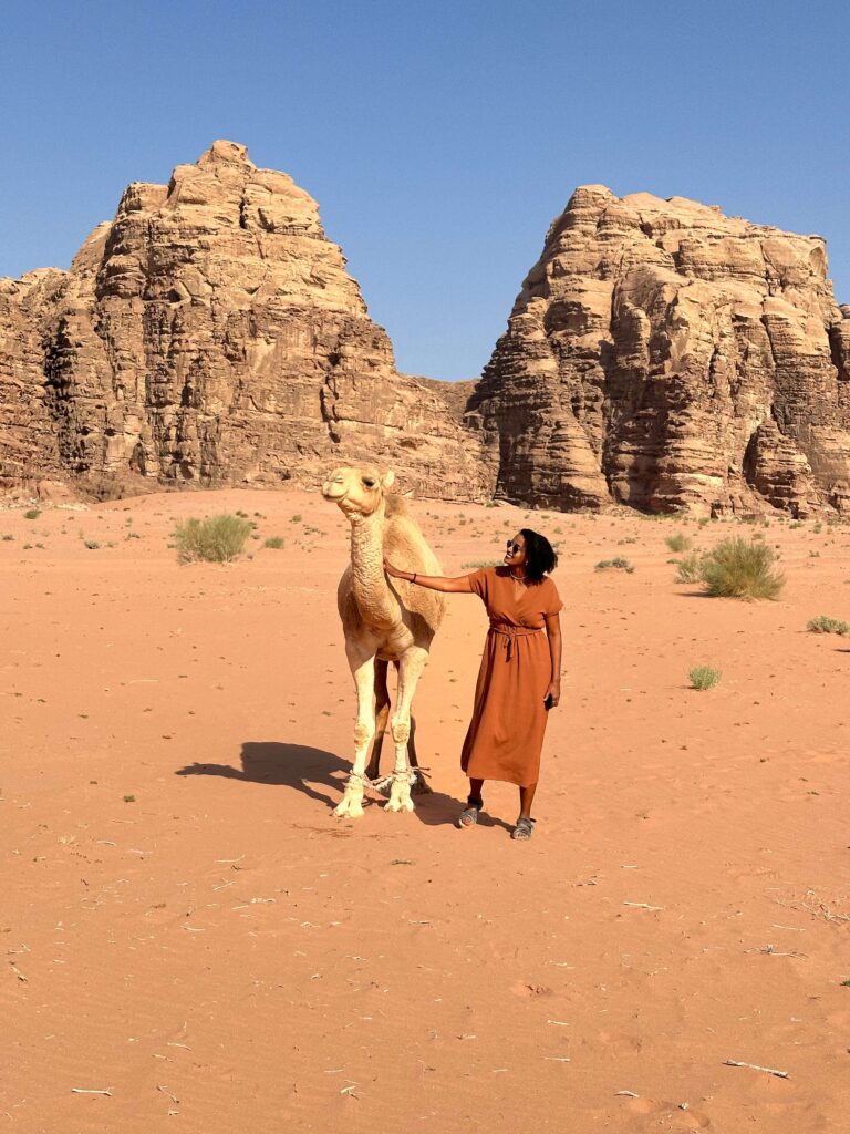 Solo female traveler riding a camel in the desert of Jordan, adventure travel experience