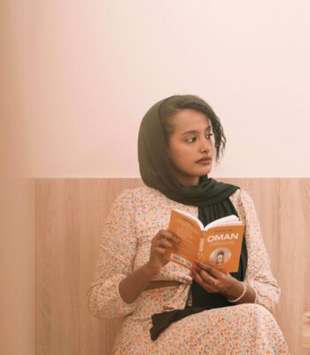Solo female traveler in Oman enjoying coffee at a cozy café while reading a book