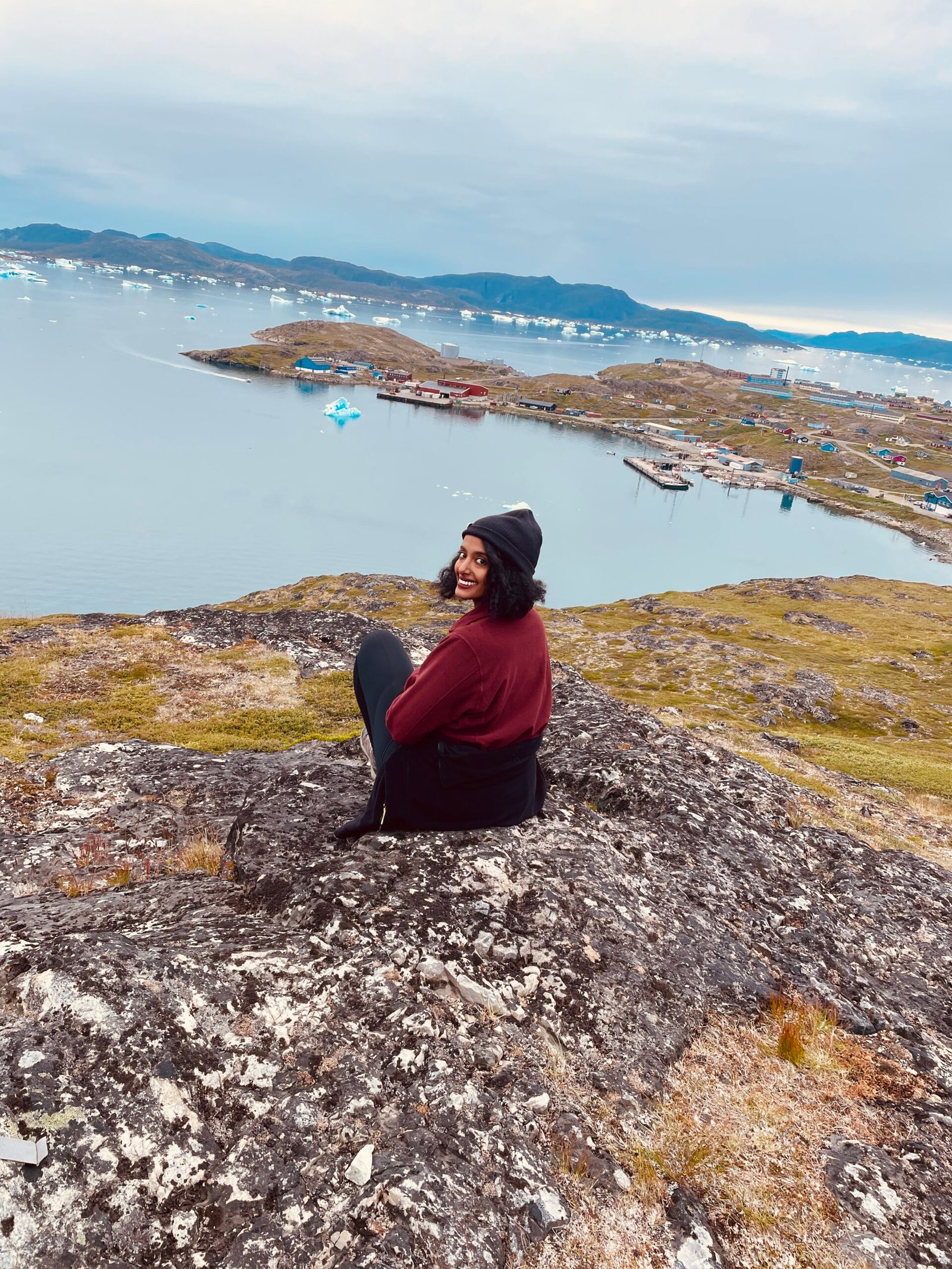 Female traveler enjoying a solo expedition in Greenland, walking across pristine snowy terrain in winter gear.
