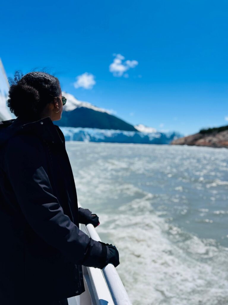 Solo female traveler in Argentina on a boat approaching a glacier, exploring the breathtaking Patagonian scenery.