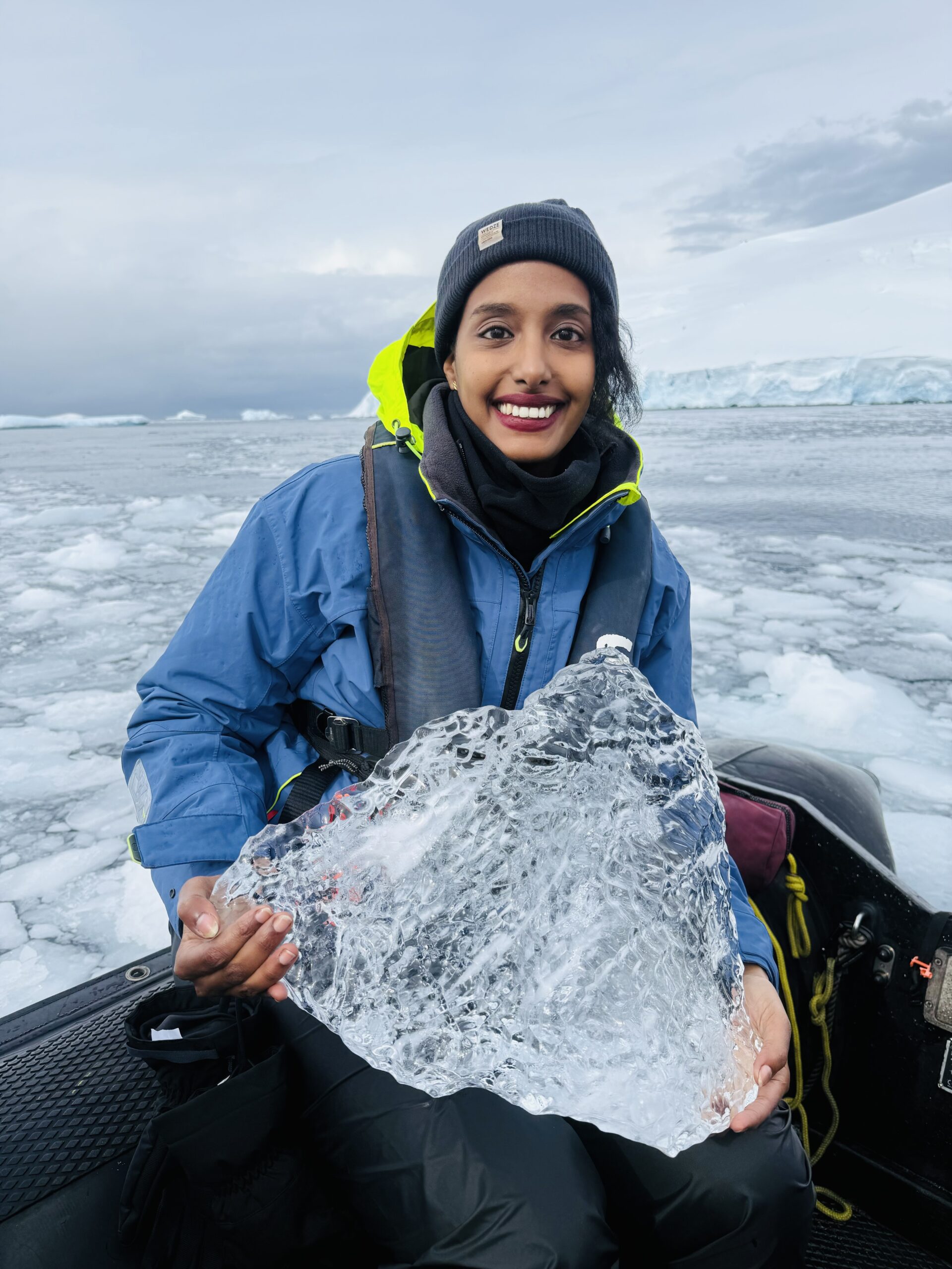 Solo female traveler exploring the icy landscapes of Antarctica, dressed in warm expedition gear, with glaciers and snow-covered terrain in the background.