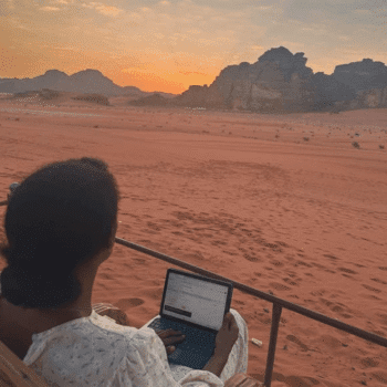 Solo female traveler working remotely in the Jordan desert, enjoying location-independent lifestyle and adventure