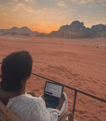 Solo female traveler working remotely in the Jordan desert, enjoying location-independent lifestyle and adventure