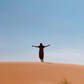 solo female traveler exploring the desert in Oman with sand dunes