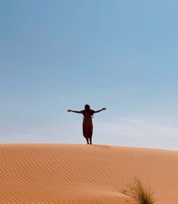solo female traveler exploring the desert in Oman with sand dunes