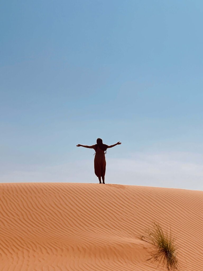 solo female traveler exploring the desert in Oman with sand dunes