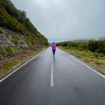 Solo female hiker walking along Madeira's scenic levada trails surrounded by lush greenery