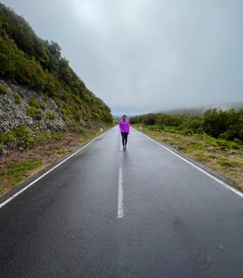 Solo female hiker walking along Madeira's scenic levada trails surrounded by lush greenery