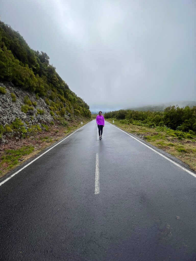 Solo female hiker walking along Madeira's scenic levada trails surrounded by lush greenery