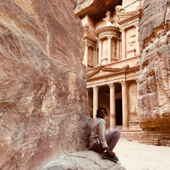 Solo female traveler exploring the ancient city of Petra in Jordan, walking through the historic rock-cut landscape