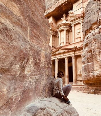 Solo female traveler exploring the ancient city of Petra in Jordan, walking through the historic rock-cut landscape