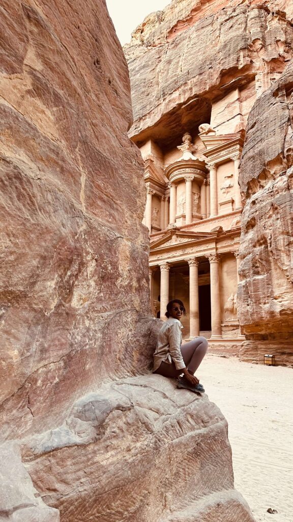 Solo female traveler exploring the ancient city of Petra in Jordan, walking through the historic rock-cut landscape