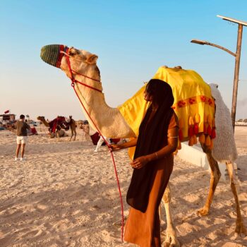 Solo female traveler riding a camel in the desert of Oman
