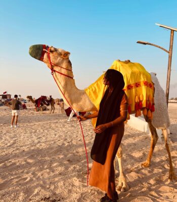 Solo female traveler riding a camel in the desert of Oman