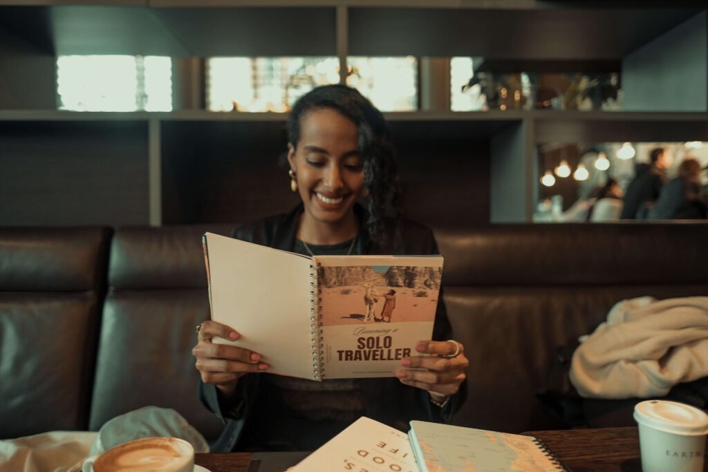 Solo female traveler and remote worker reading a travel book in a coffee shop