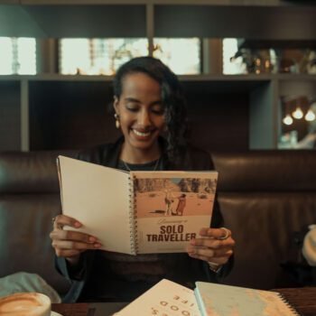 Solo female traveler and remote worker reading a travel book in a coffee shop