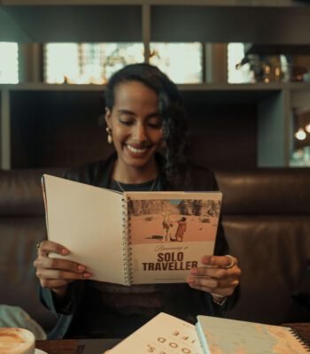 Solo female traveler and remote worker reading a travel book in a coffee shop