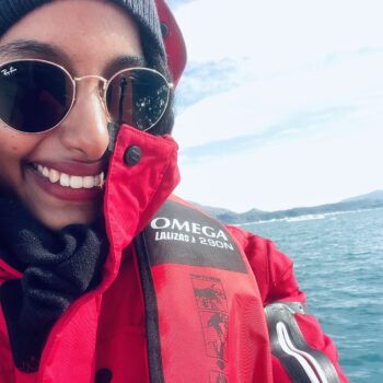 Solo female traveler on zodiac boat enjoying Greenland iceberg views during Arctic adventure