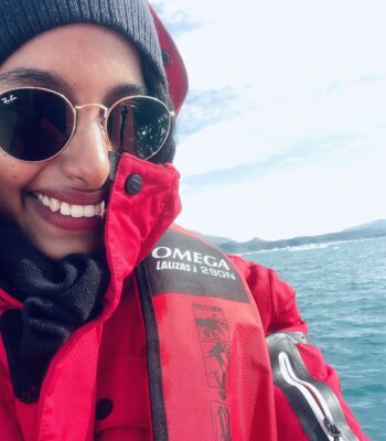 Solo female traveler on zodiac boat enjoying Greenland iceberg views during Arctic adventure