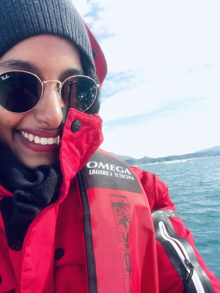 Solo female traveler on zodiac boat enjoying Greenland iceberg views during Arctic adventure