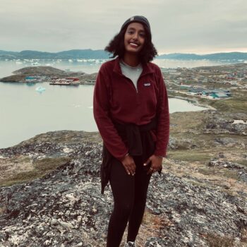 Solo female traveler hiking in Greenland mountains surrounded by Arctic wilderness