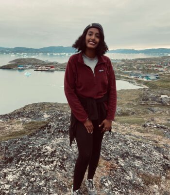 Solo female traveler hiking in Greenland mountains surrounded by Arctic wilderness