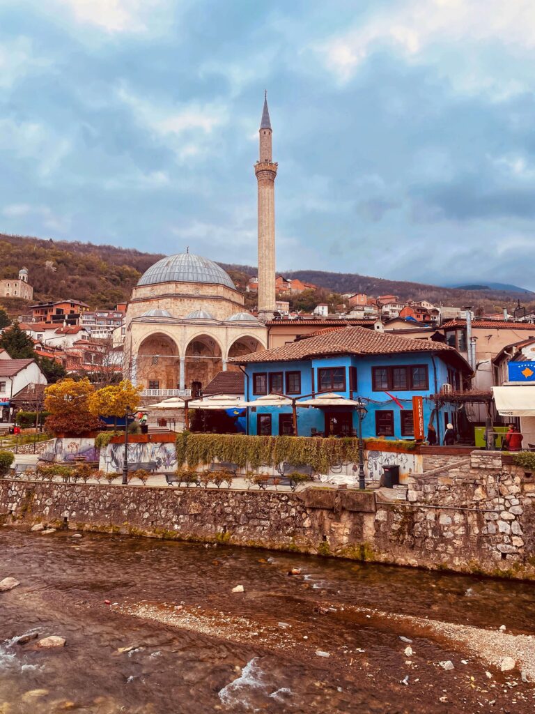 Solo female traveler walking through the old town of Prizren in Kosovo with historic stone streets and river views