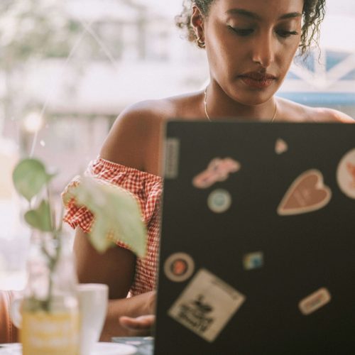Female freelancer and travel mentor working from a laptop ina coffee shop